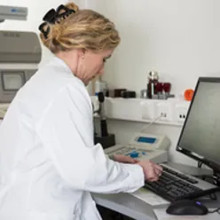 En person i hvit frakk som arbeider på en datamaskin