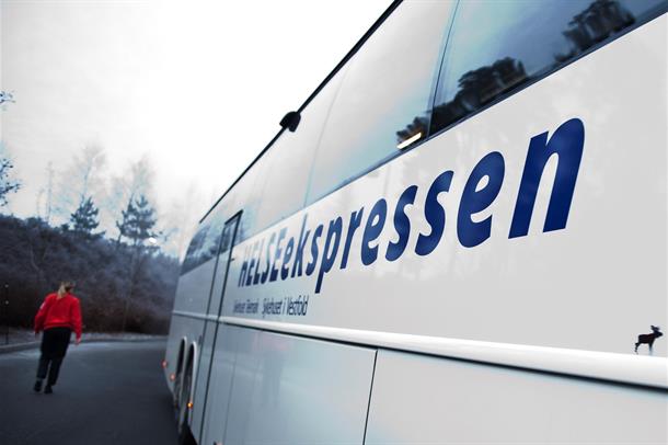 En person som går ved siden av en hvit buss
