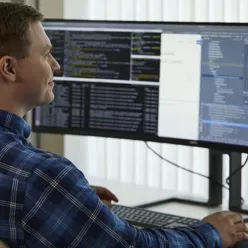 En mann som sitter ved et skrivebord og ser på en dataskjerm
