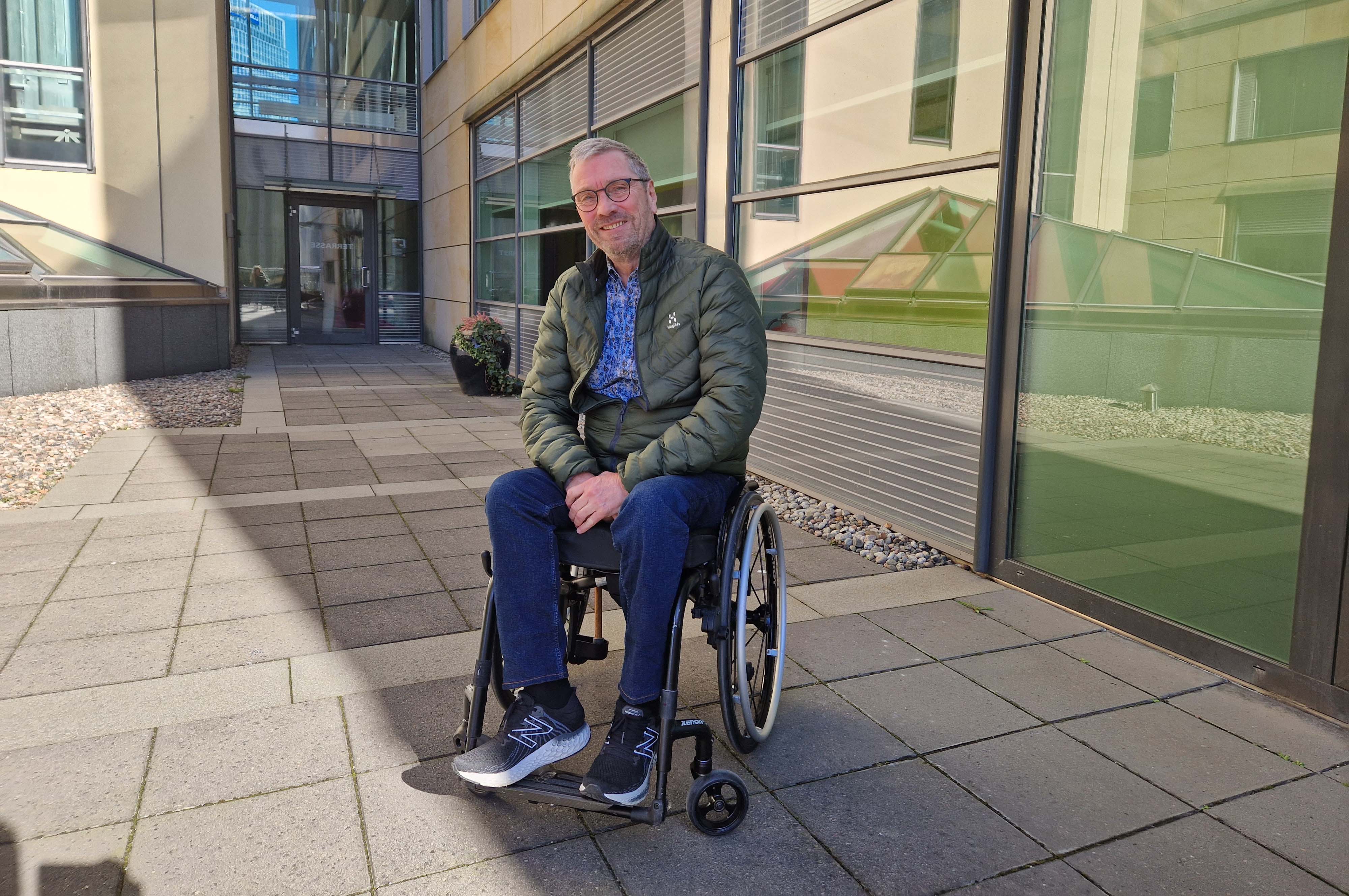 En person som sitter i rullestol utenfor en bygning